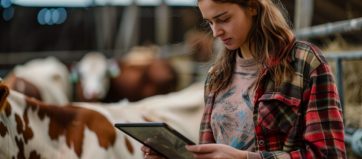 Shot of a young woman using a digital tablet while working at a cow farm